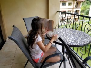 My Homeschooling Review After One Interesting Year - Faith reading on the balcony